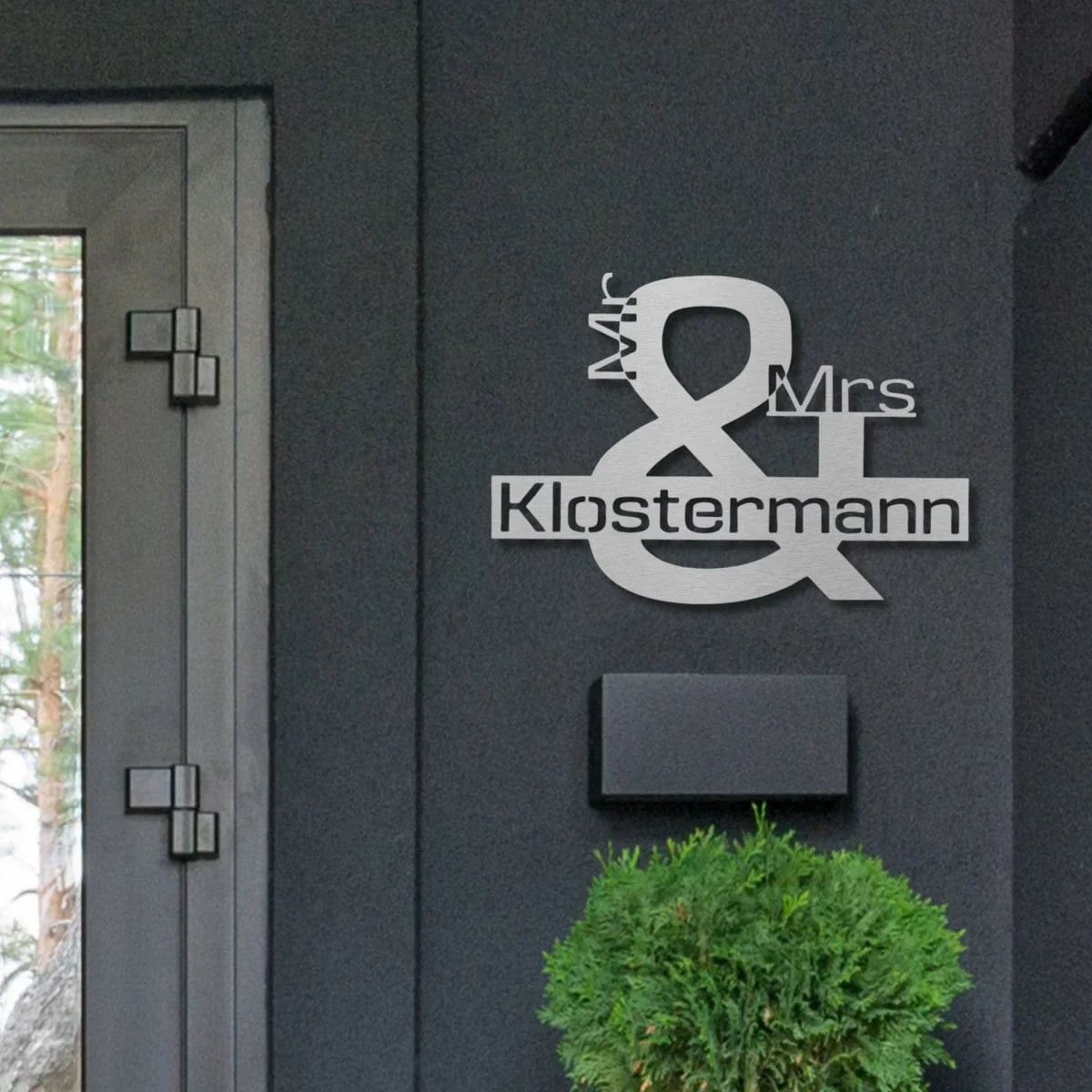 Ein schickes Schild mit dem Motiv Mr & Mrs Klostermann aus Edelstahl hängt an der Wand neben der Haustür