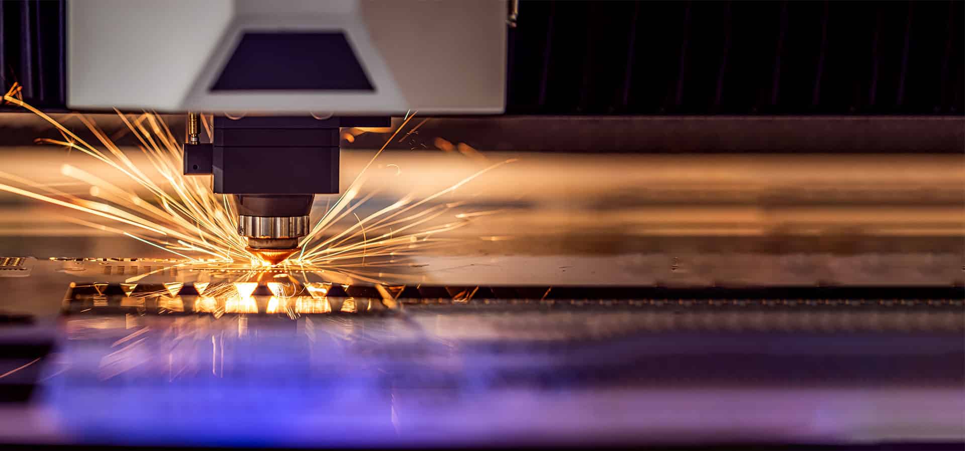 Nahaufnahme eines Brennkopfes einer Lasermaschine, der gerade Stahl schneidet mit Funken