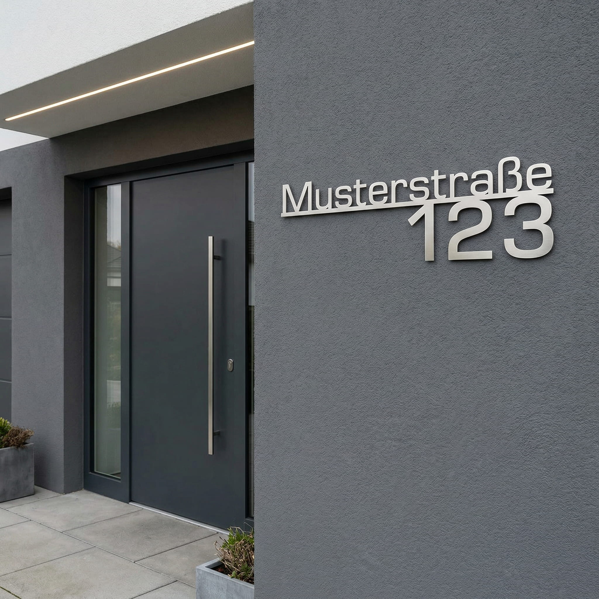 Hauseingang mit einem Schild aus Edelstahl auf der die Straße und Hausnummer zu sehen sind.