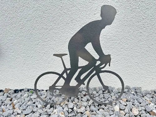 Gartenstecker mit dem Motiv eines Radfahrers aus Cortenstahl noch ungerostet in einem Steinbeet